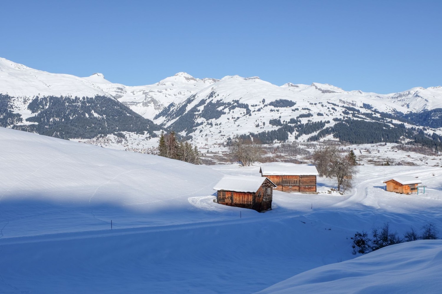 Die morgendlich besonnten Berge auf der anderen Talseite der Surselva während in Obersaxen die Schatten noch lang sind.