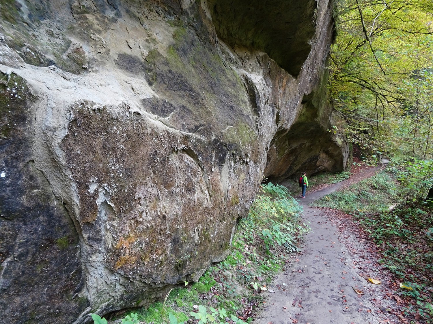 L’homme semble si petit sous l’immense paroi de molasse.