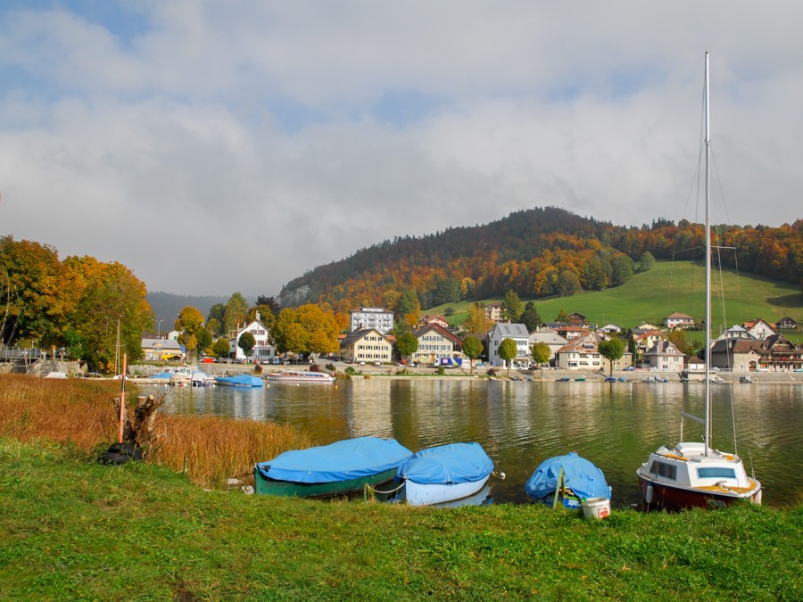 Le Pont erstreckt sich über einen schmalen Uferbereich zwischen See und den Berghängen dahinter.