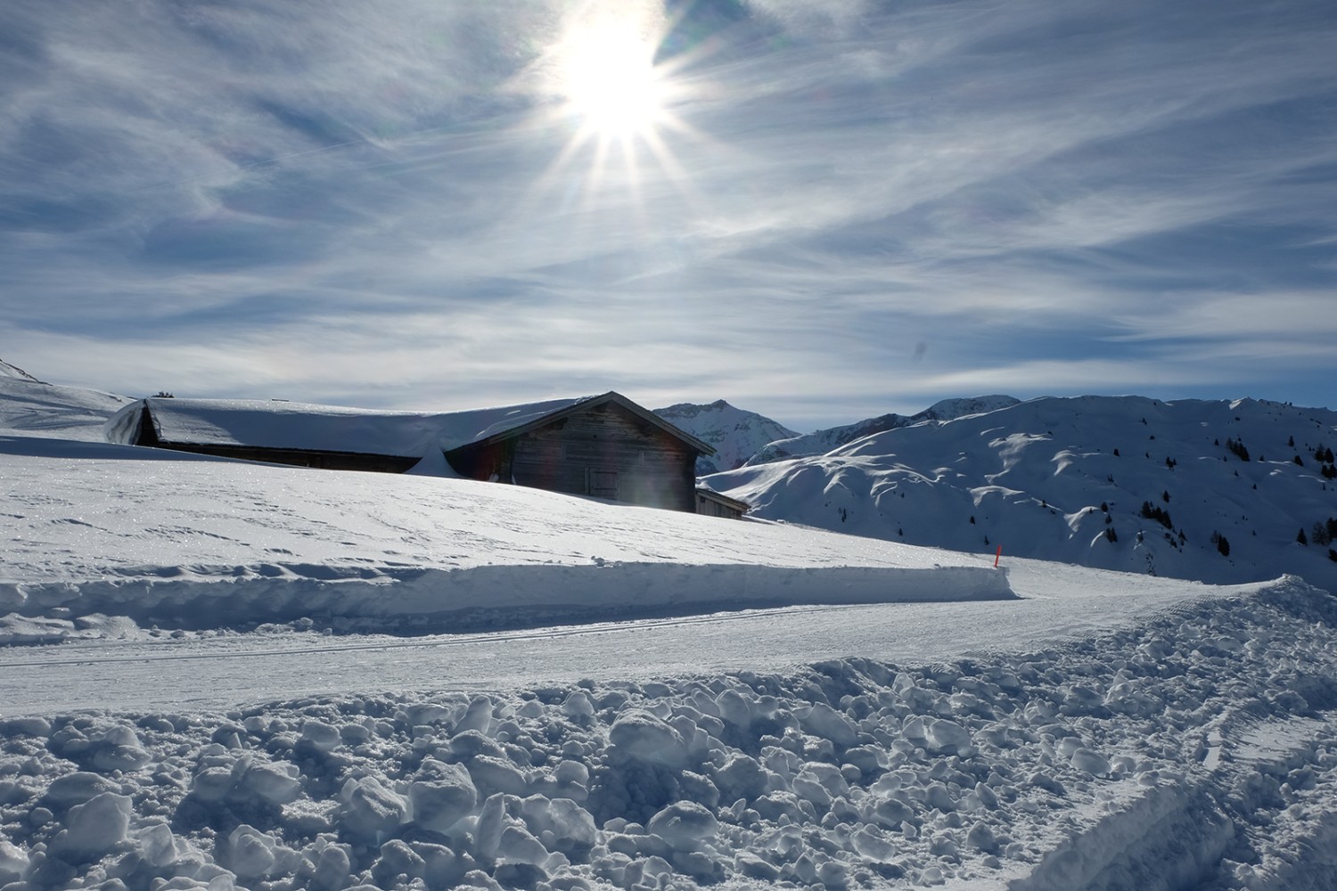 Les fondeurs et les randonneurs passent près de cabanes d’alpages aux toits couverts de neige.